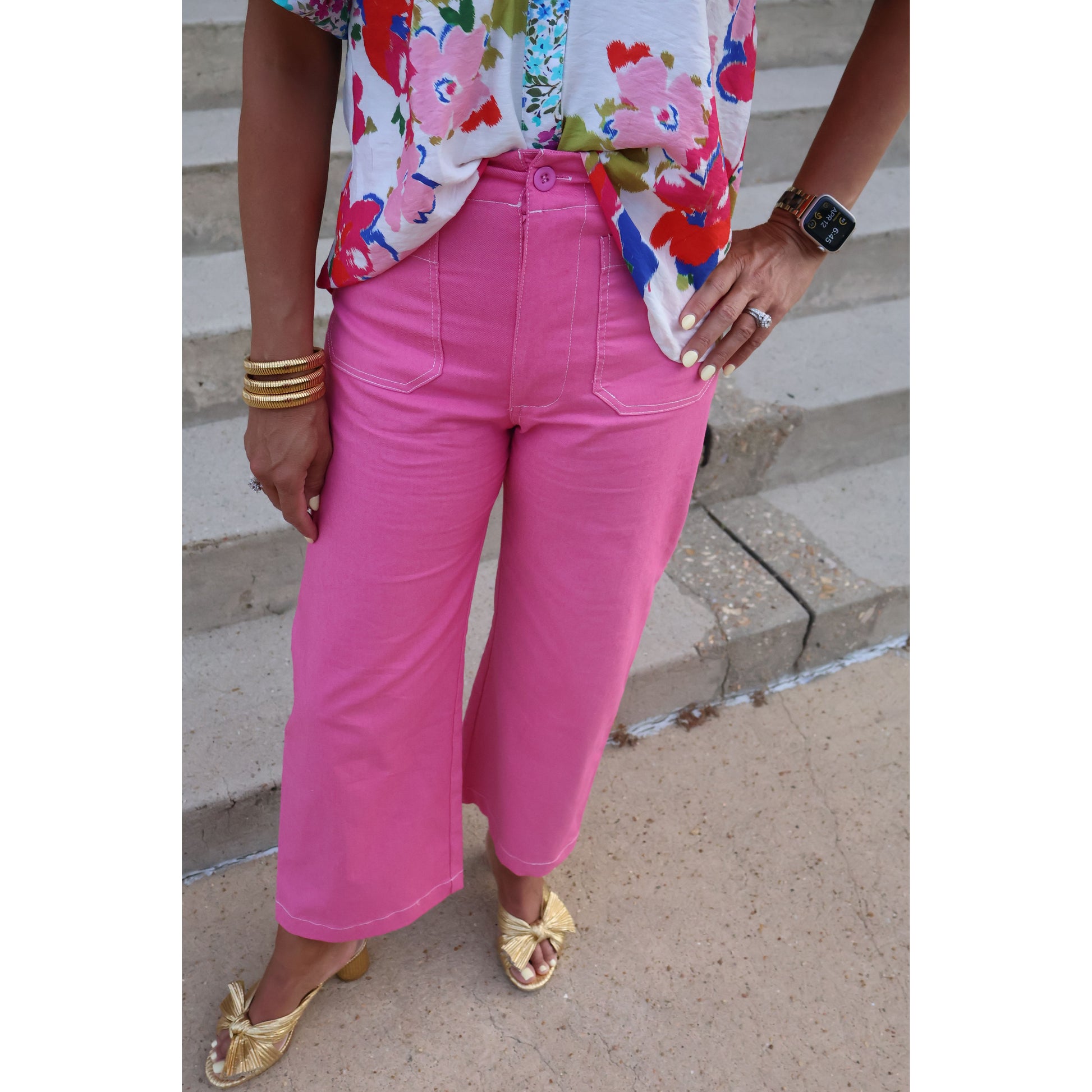 Person wearing bright pink pants and a colorful top, standing on a concrete surface.