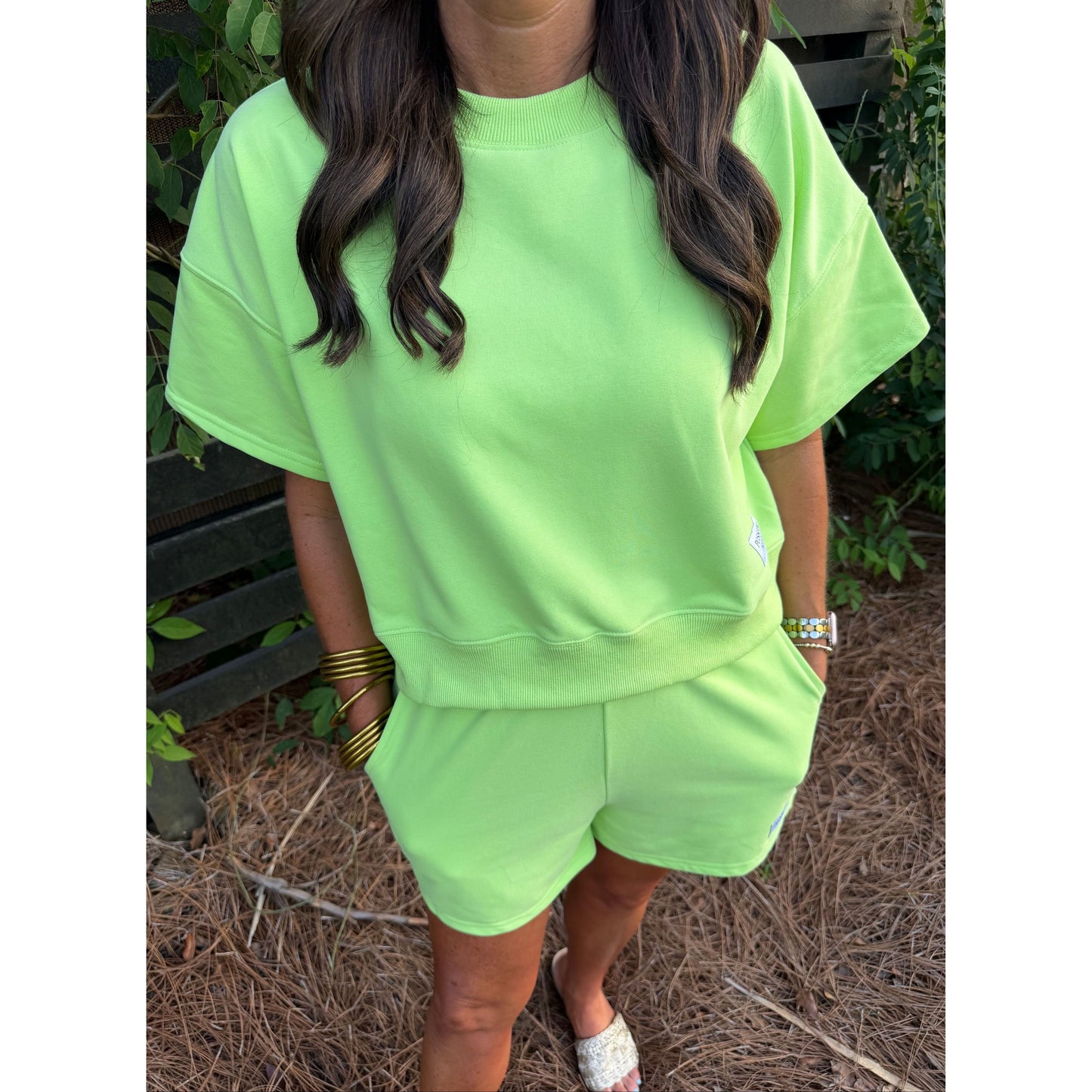 Person wearing a bright green outfit with a matching top and shorts, standing outdoors.
