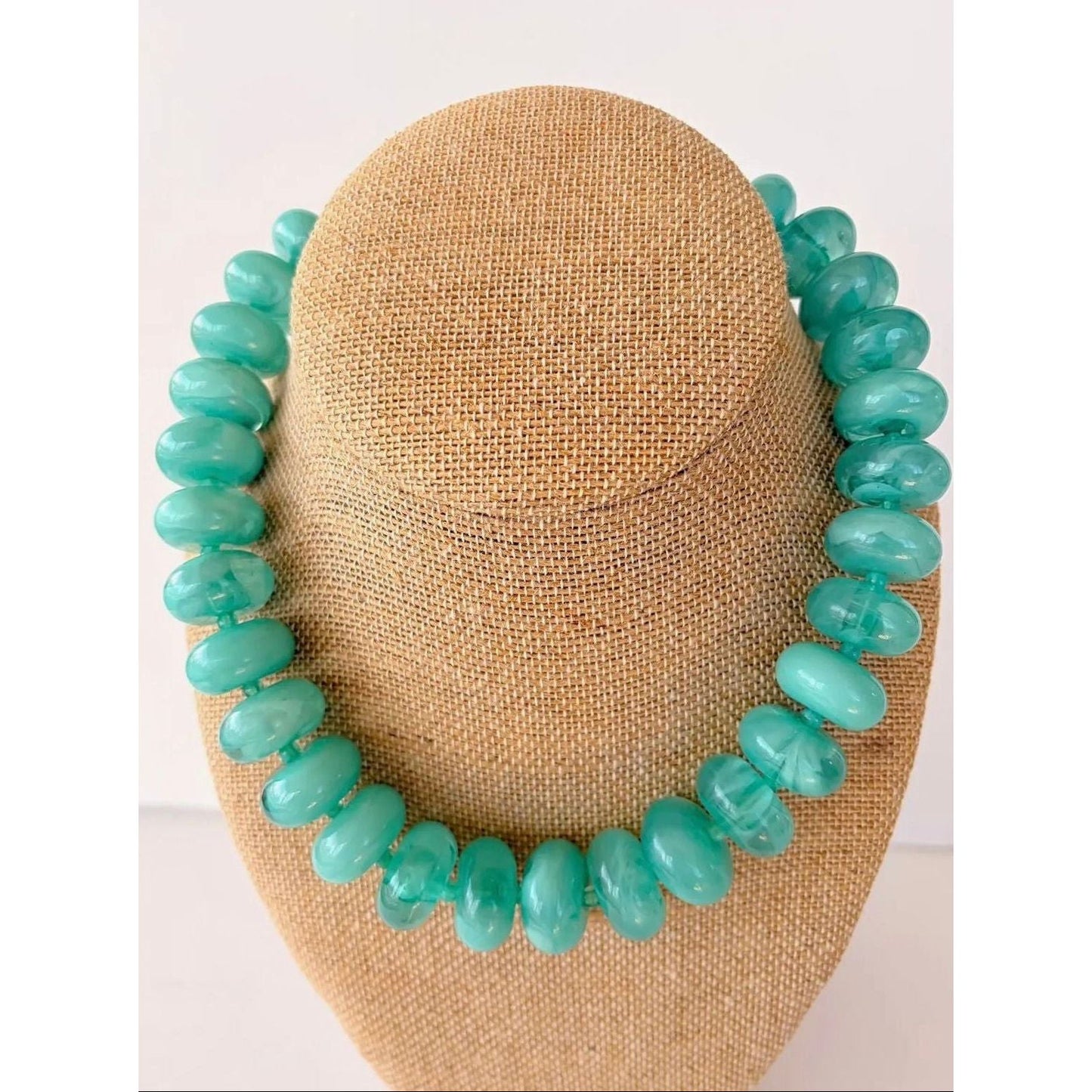 Turquoise beaded necklace on a mannequin head against a white background