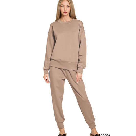 Woman wearing a beige sweatshirt and pants set on a white background