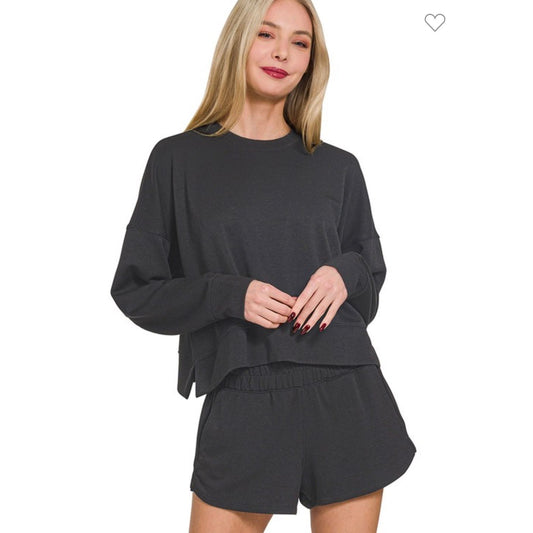 Woman wearing a black long-sleeve top and shorts set on a white background