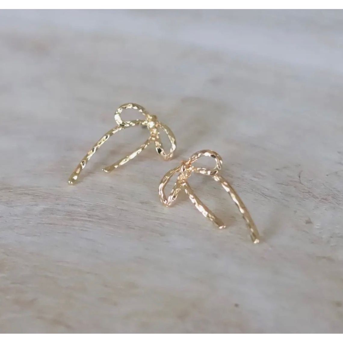 Gold earrings on a light wooden surface