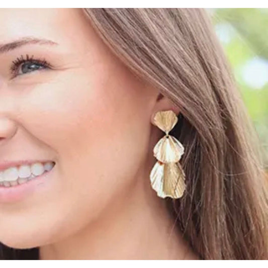 Woman wearing gold earrings with a blurred outdoor background