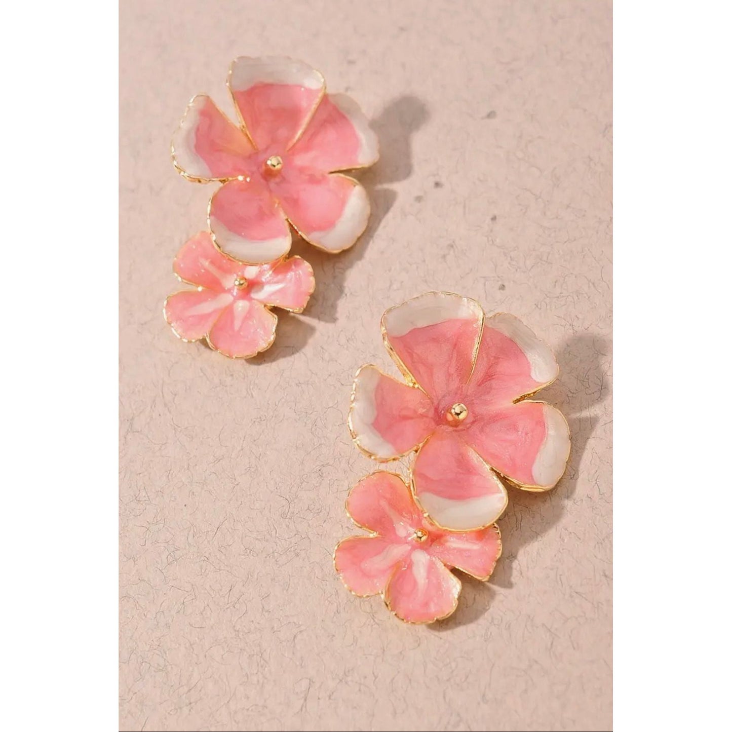Pair of pink flower earrings on a beige background