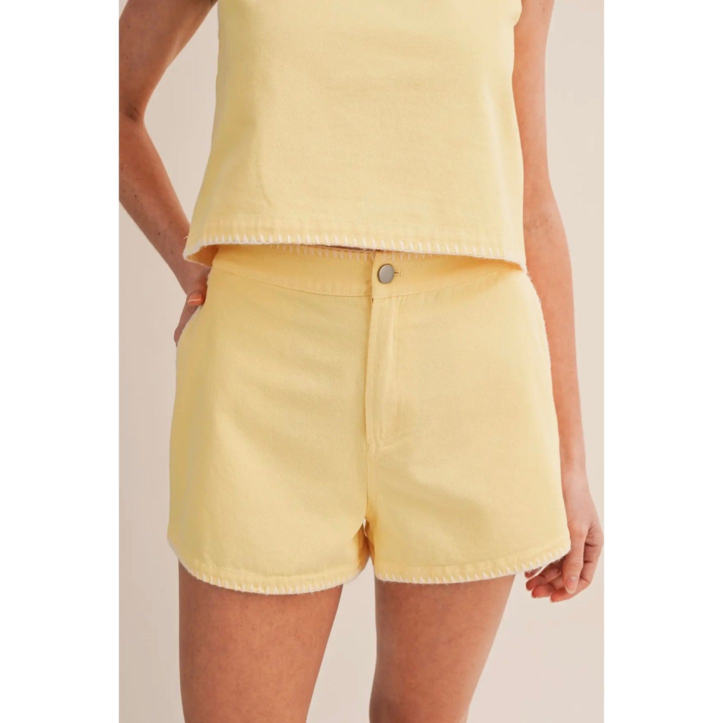 Person wearing a yellow top and shorts on a plain background