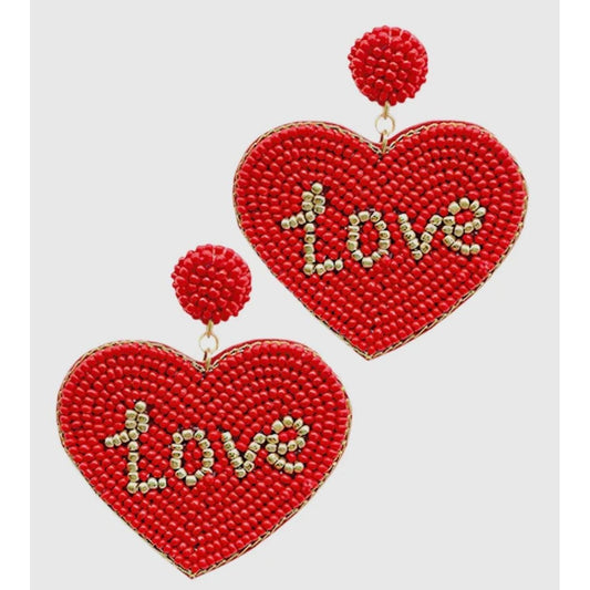 Red heart-shaped earrings with 'love' text on a light gray background