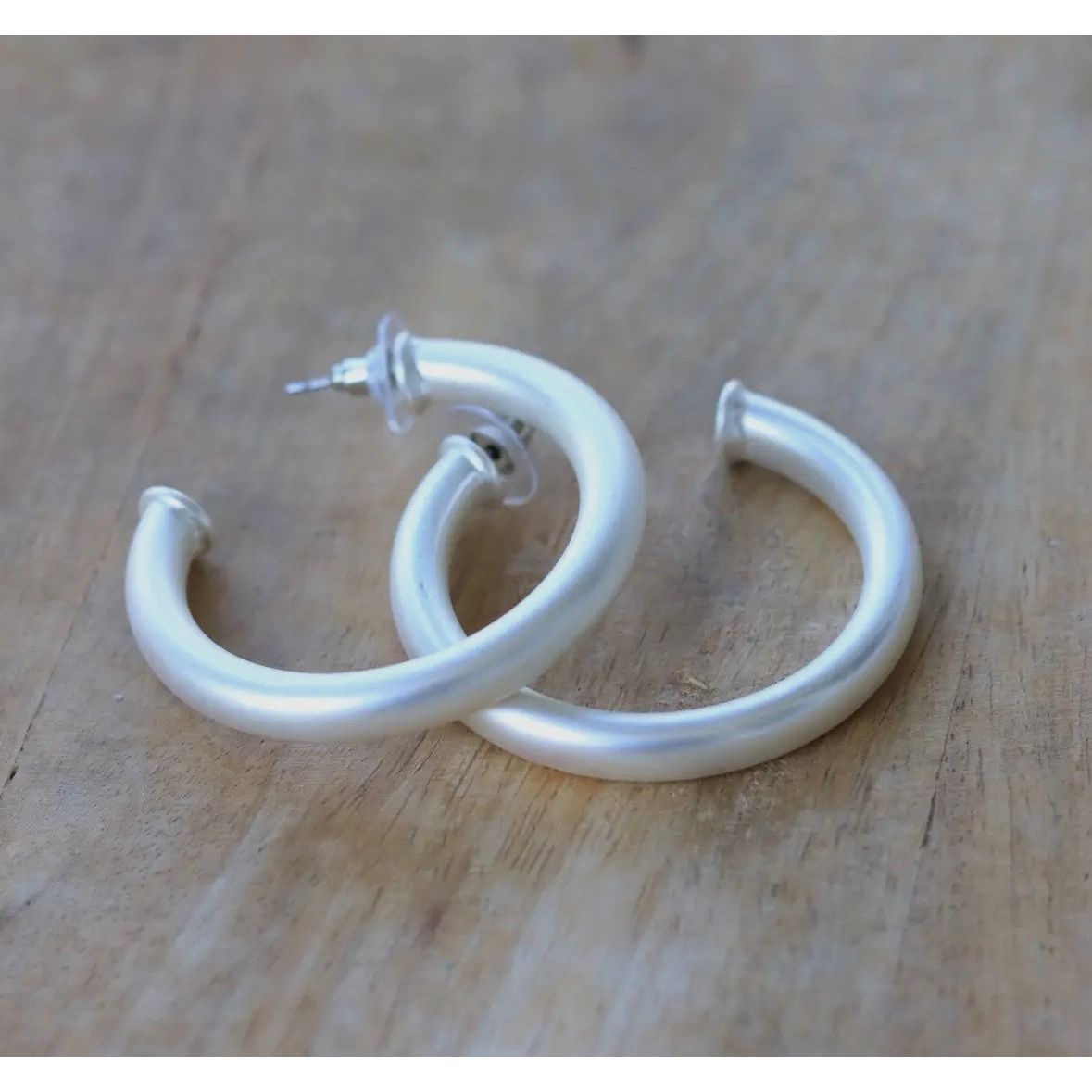White hoop earrings on a wooden surface