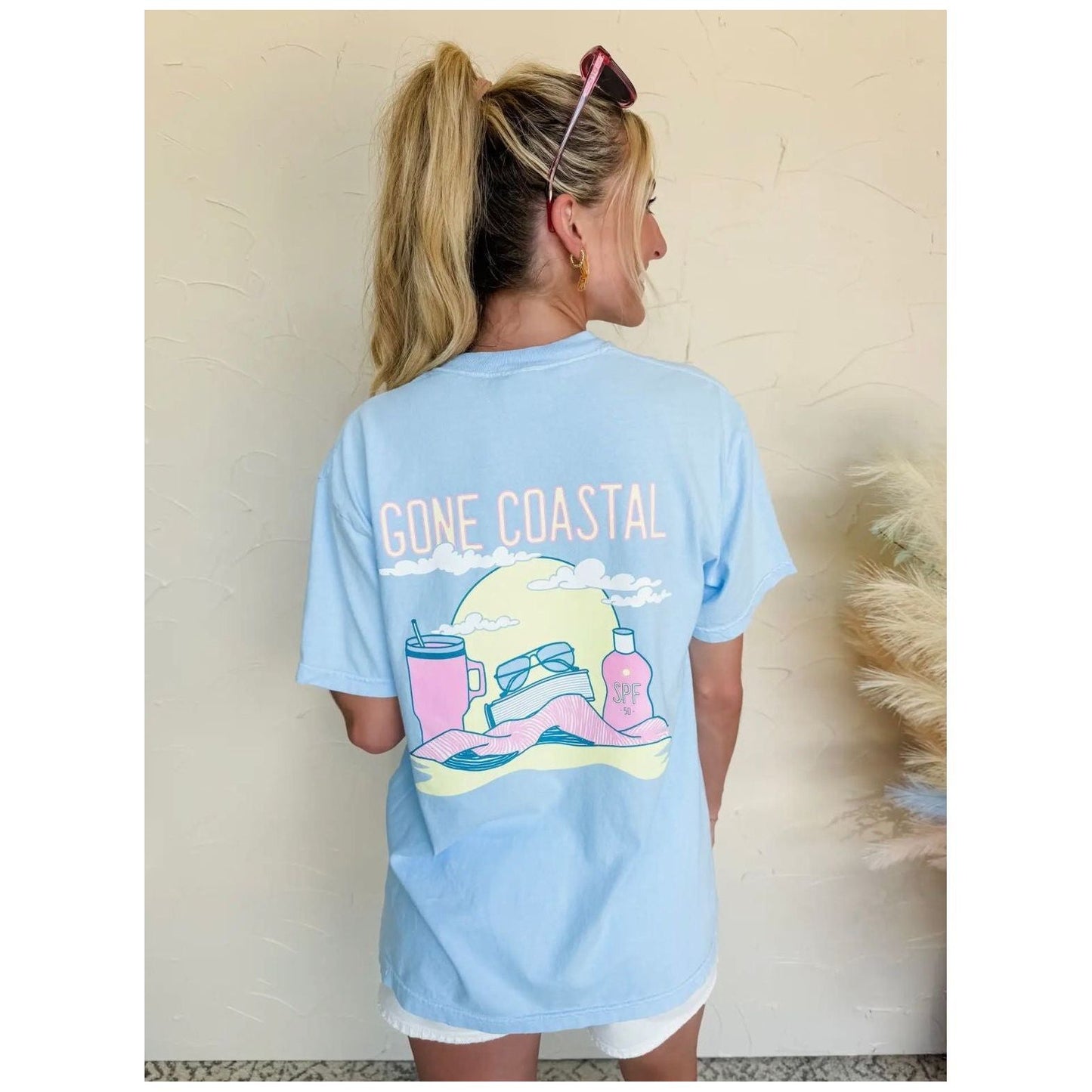 Person wearing a light blue 'Gone Coastal' t-shirt with a graphic design.