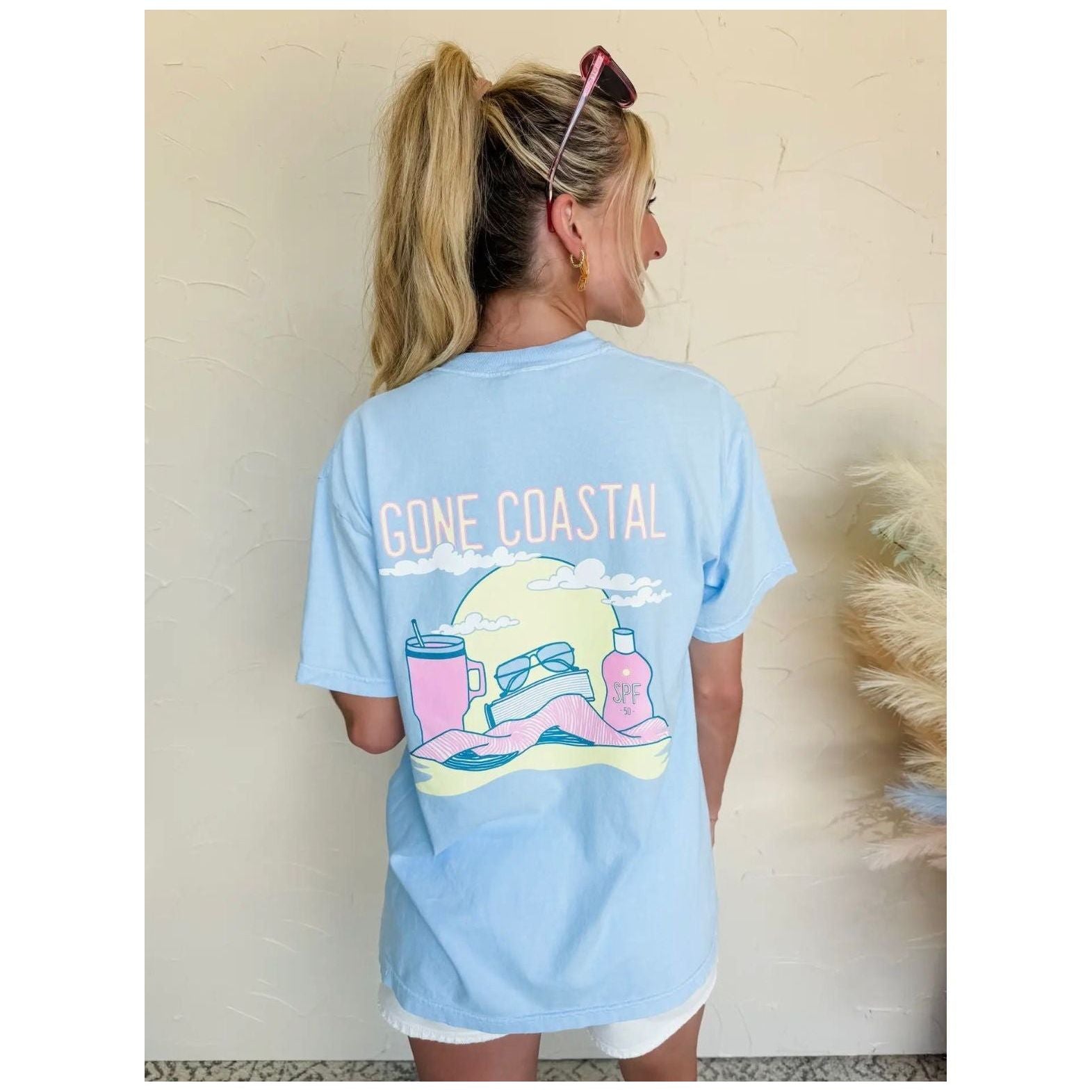 Person wearing a light blue 'Gone Coastal' t-shirt with a graphic design.