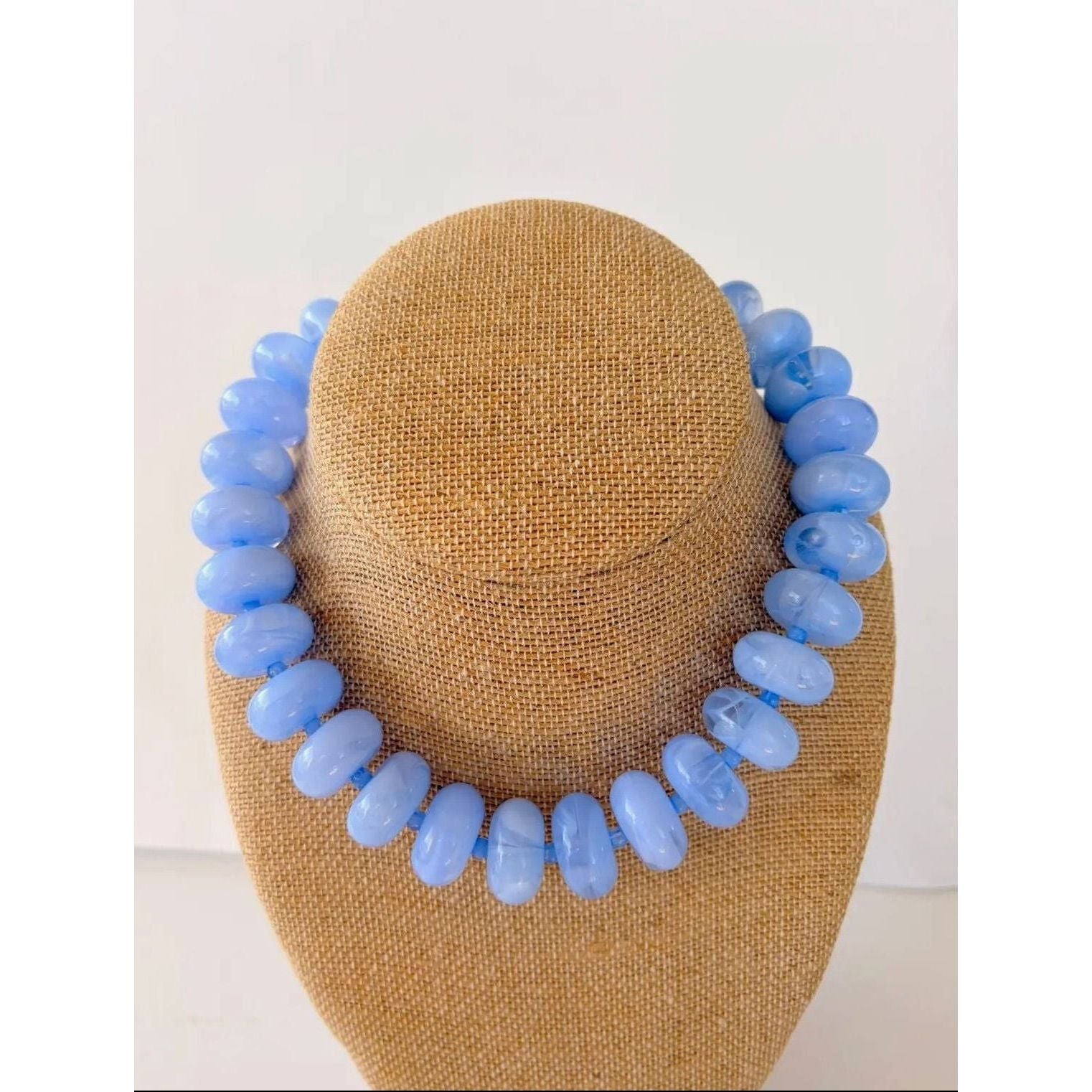 Blue beaded necklace on a mannequin head against a white background