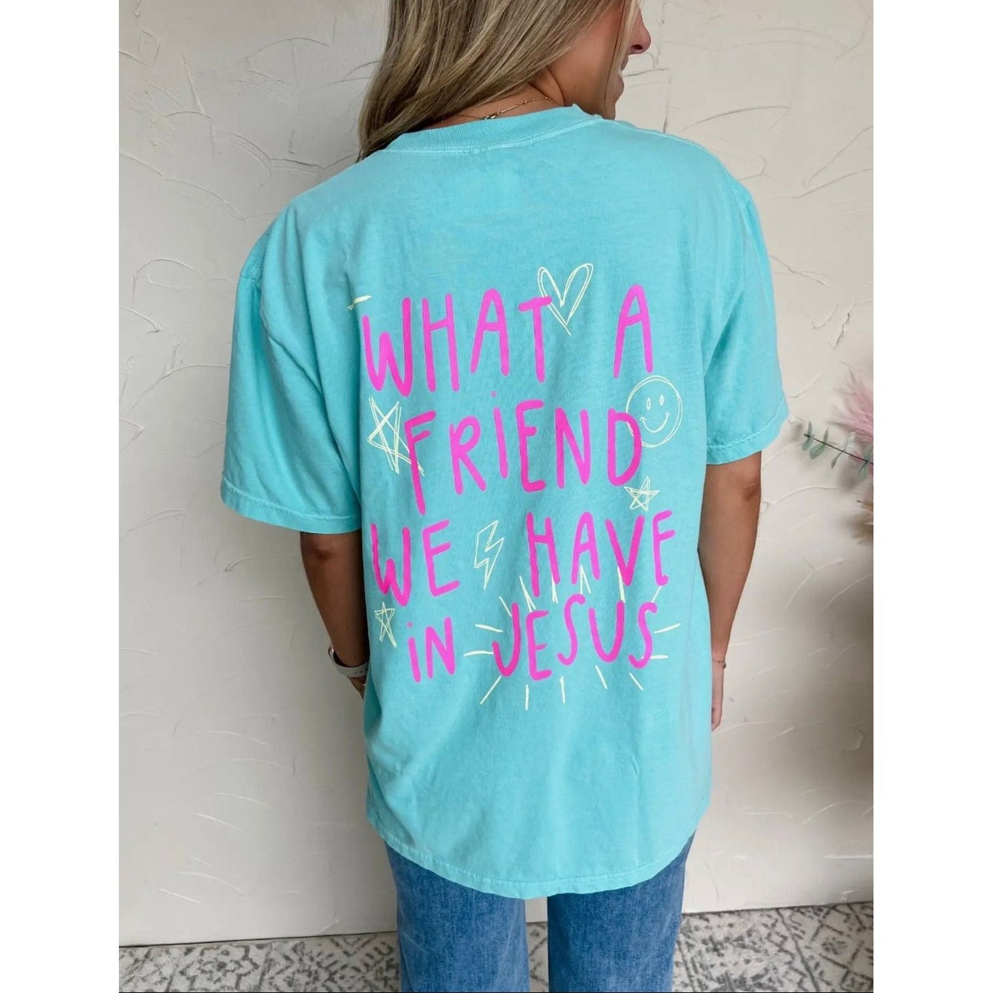 Person wearing a light blue t-shirt with pink text against a neutral background
