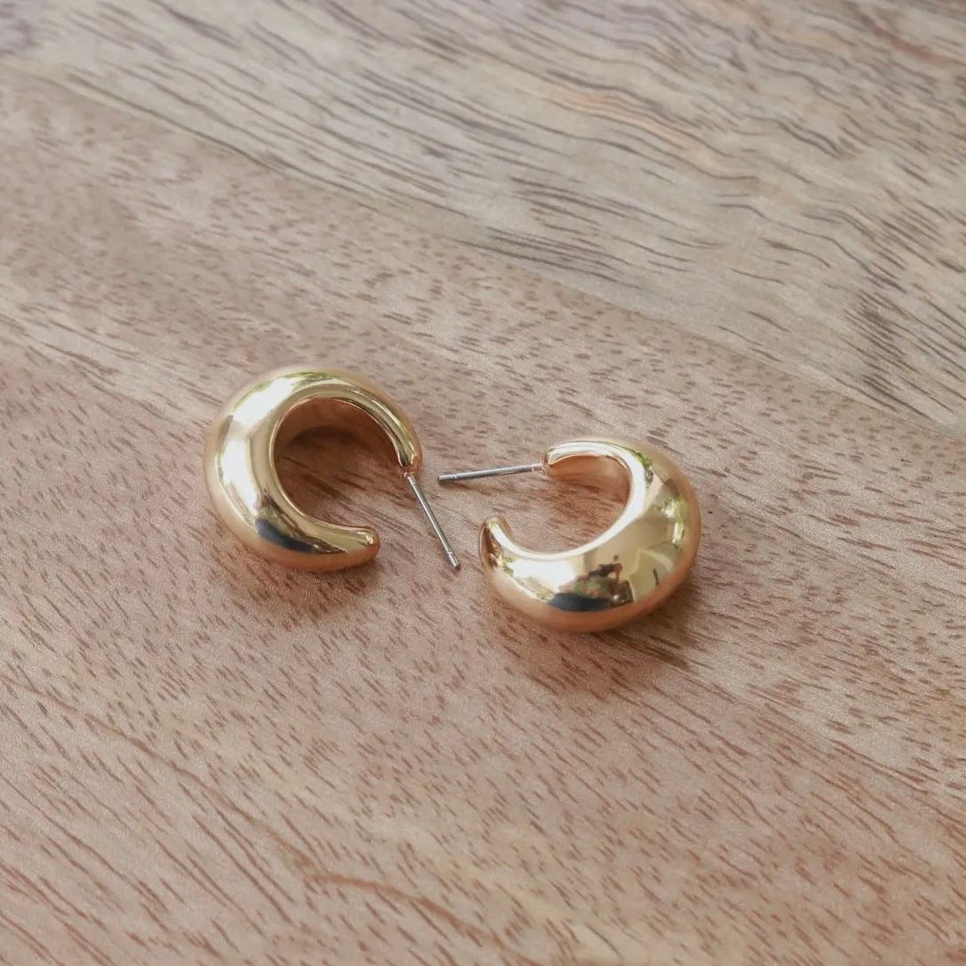 Gold hoop earrings on a wooden surface