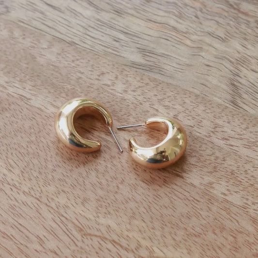Gold hoop earrings on a wooden surface