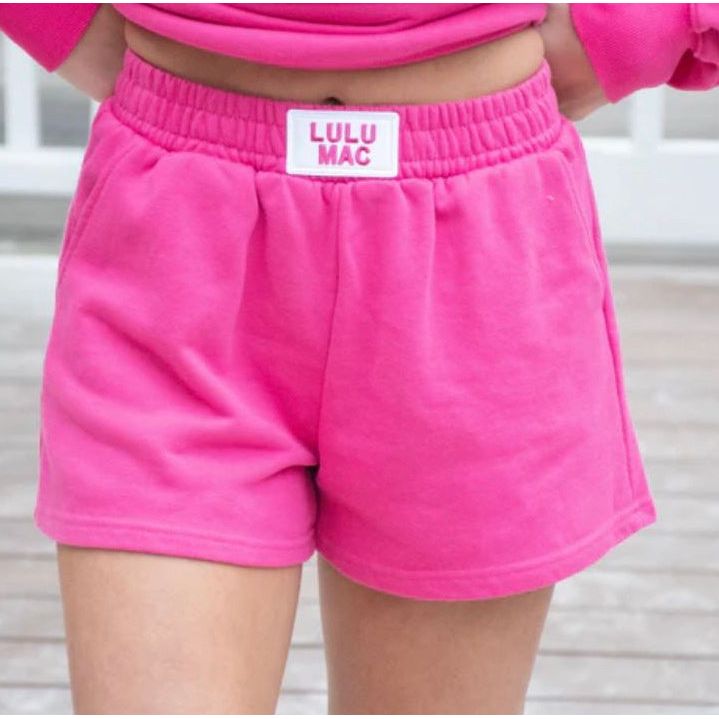 Person wearing pink shorts with a visible brand label, standing against a neutral background.