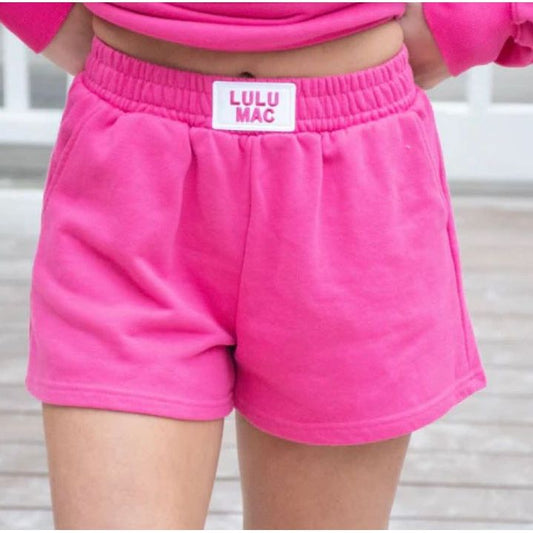 Person wearing pink shorts with a visible brand label, standing against a neutral background.