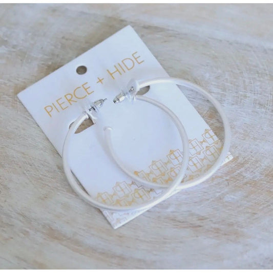 Silver hoop earrings on a Pierce + Hide branded card with a light wooden background
