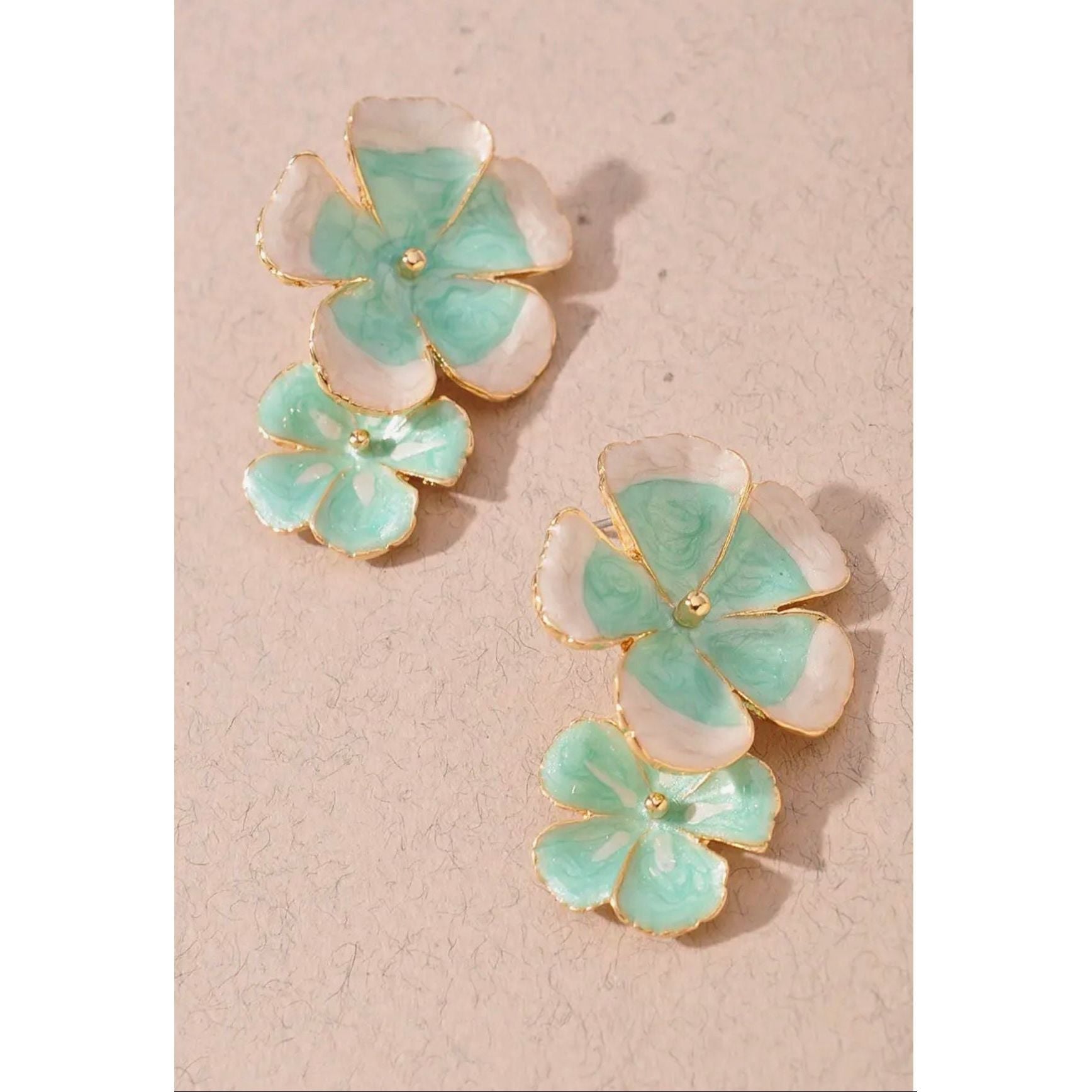 Floral earrings with green and gold details on a beige background