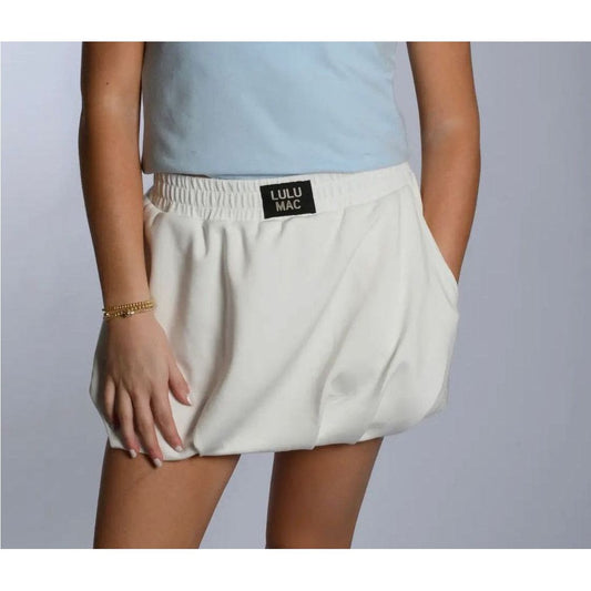 Person wearing a white skirt with a visible brand label on a plain background