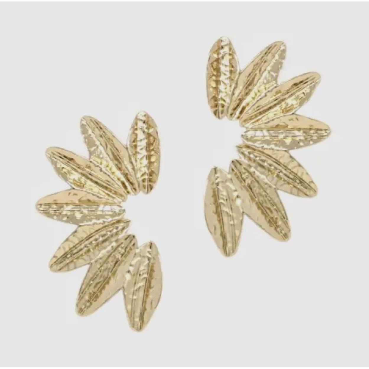 Gold floral earrings on a light gray background