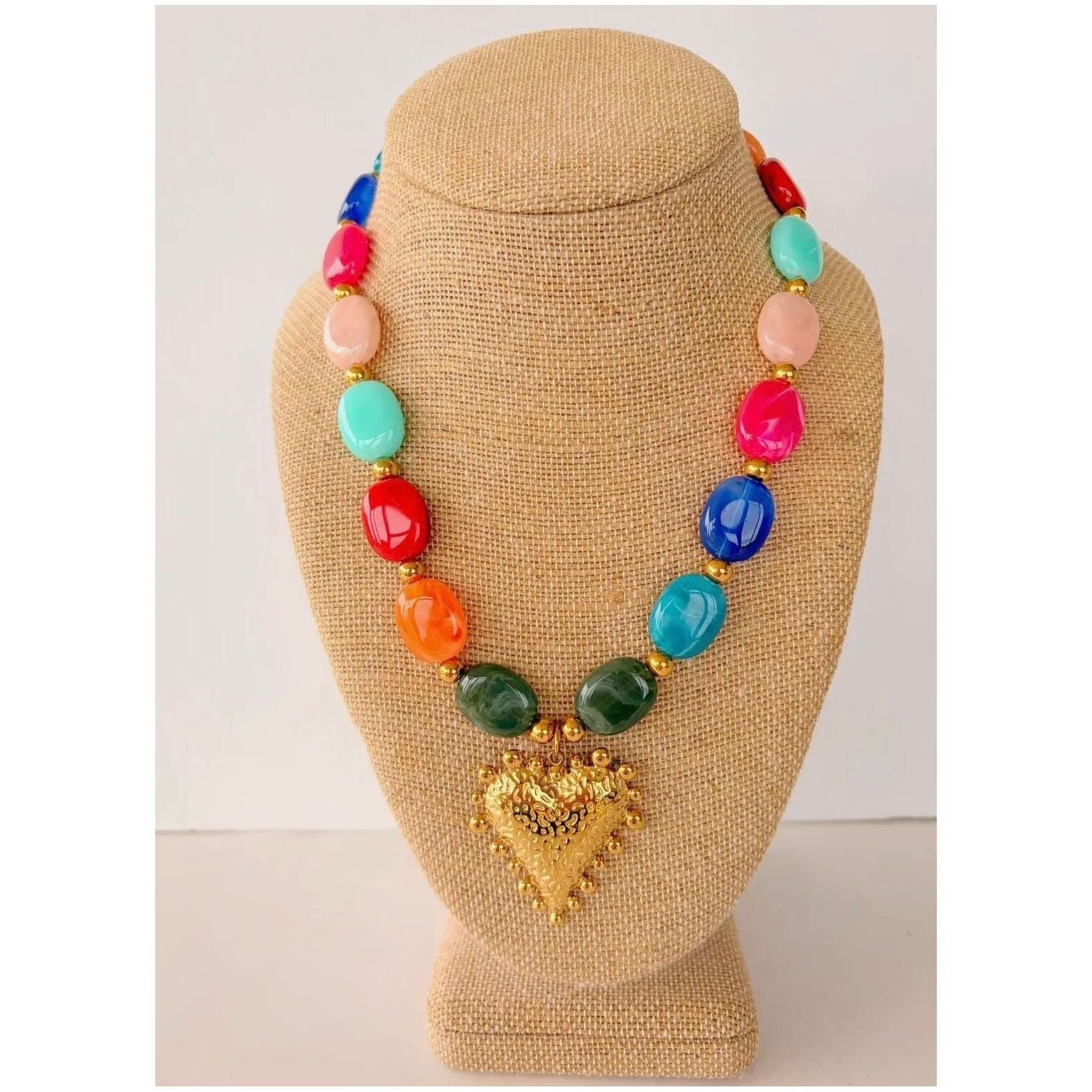 Colorful beaded necklace with a gold heart pendant on a tan mannequin bust.