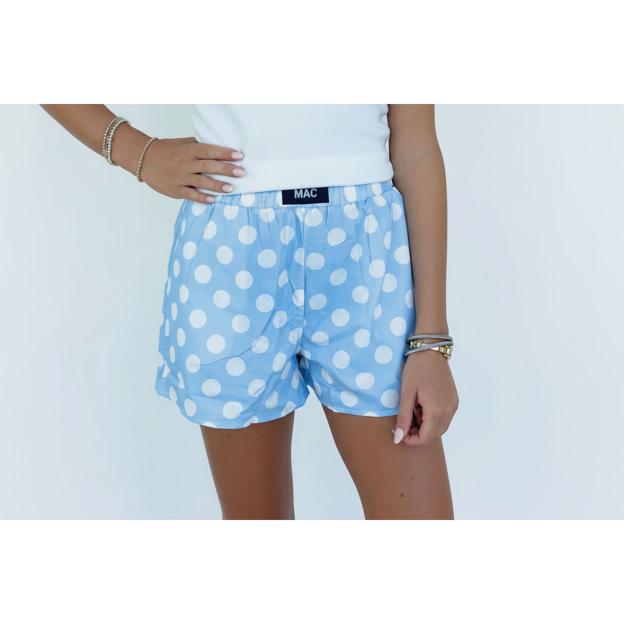 Person wearing blue polka dot shorts with a white brick wall background