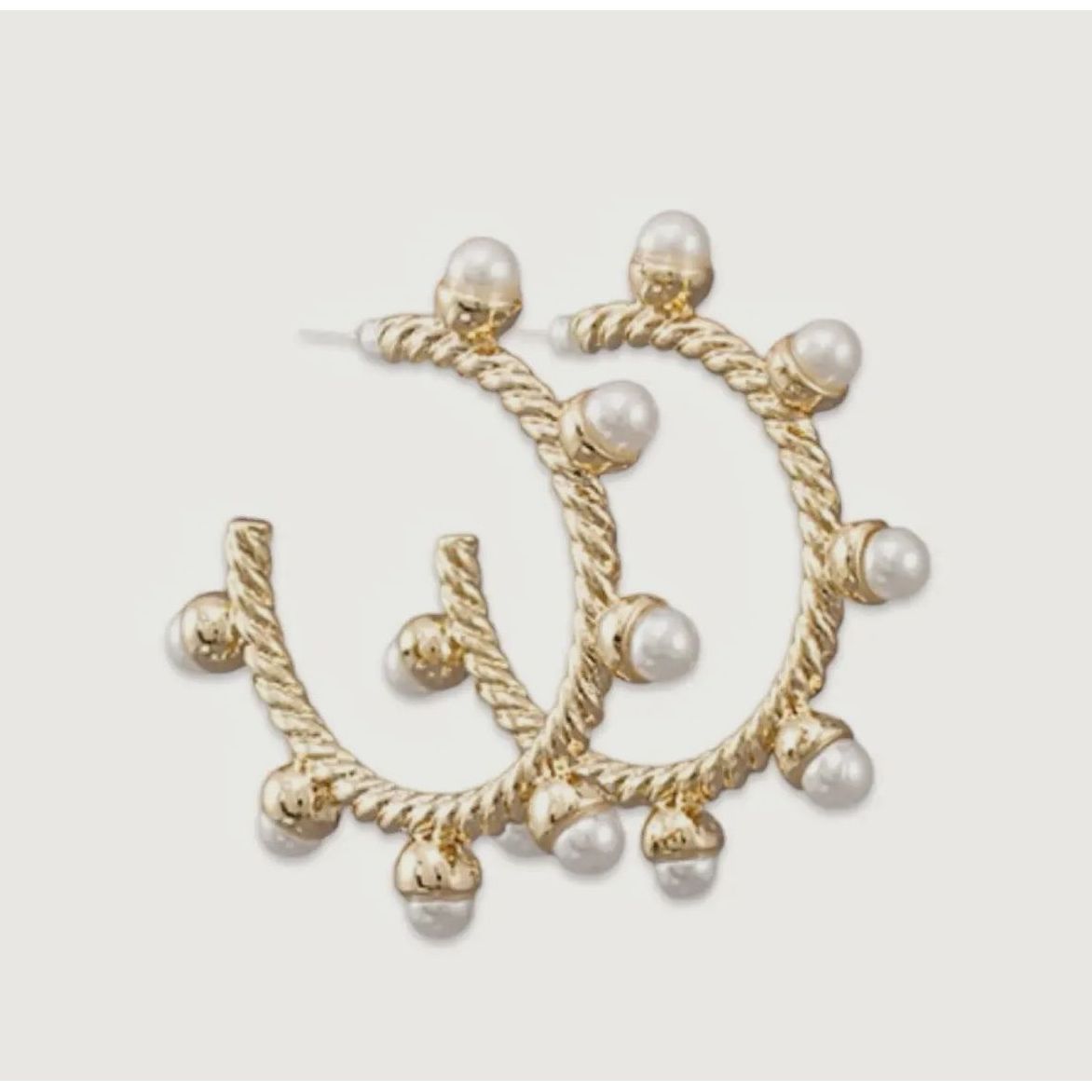 Gold hoop earrings with pearl accents on a light gray background