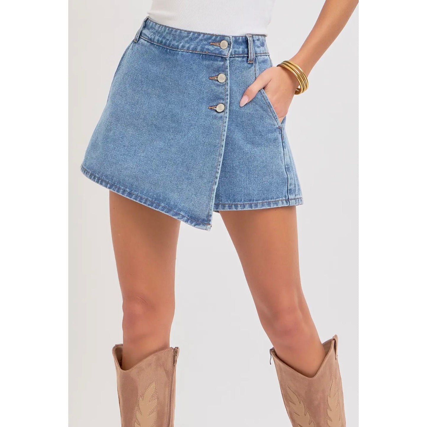 Denim skirt worn by a person with beige boots on a white background
