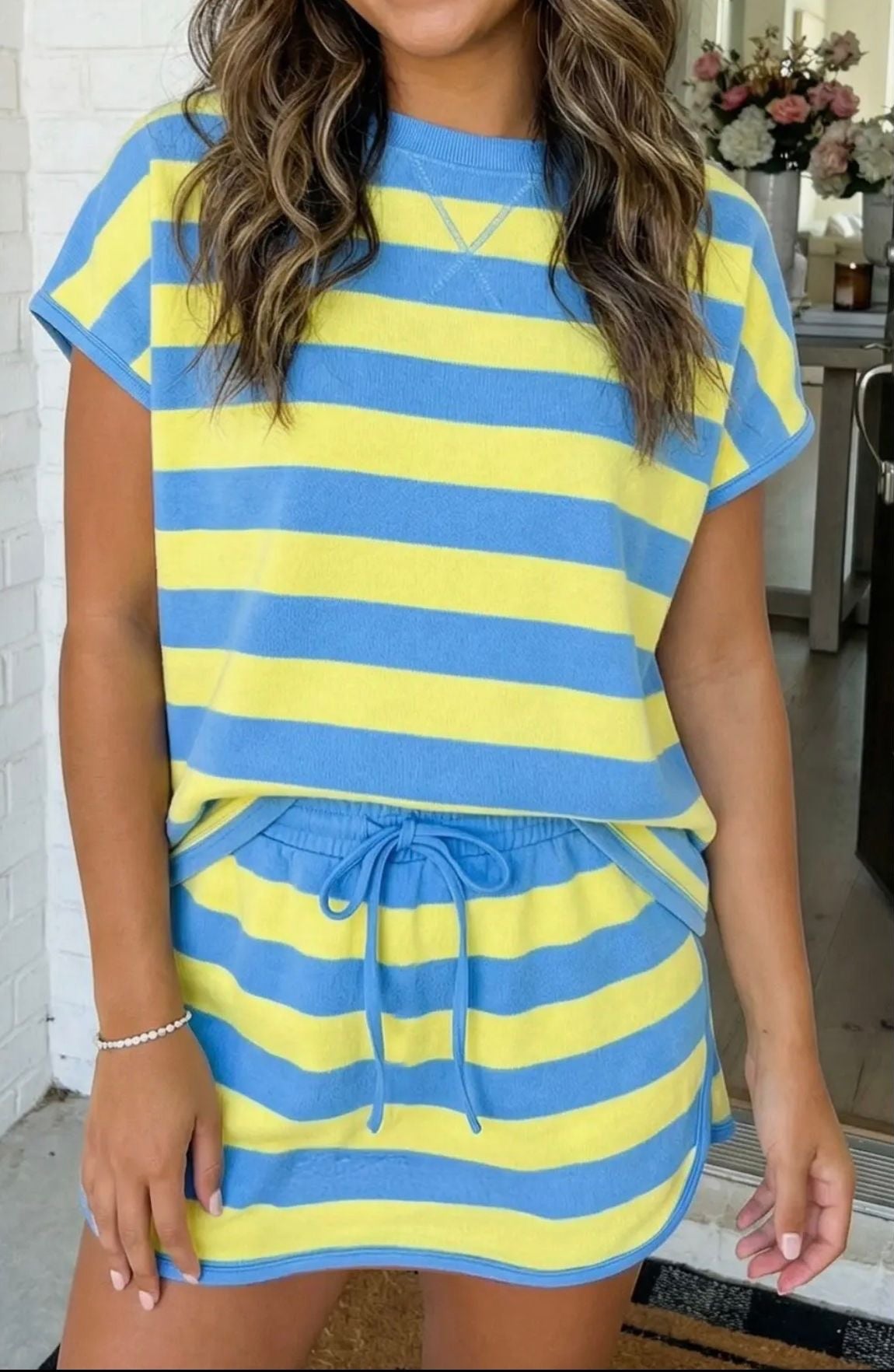Woman wearing a blue and yellow striped outfit in an indoor setting.