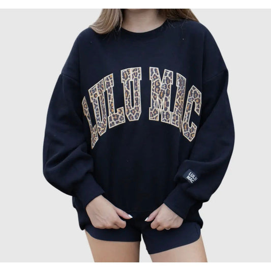 Person wearing a navy blue sweatshirt with 'LULUMAC printed in leopard print on a plain background