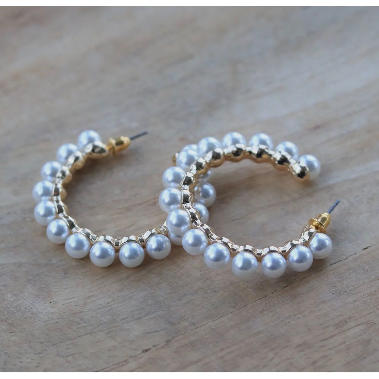 Pearl hoop earrings on a wooden surface