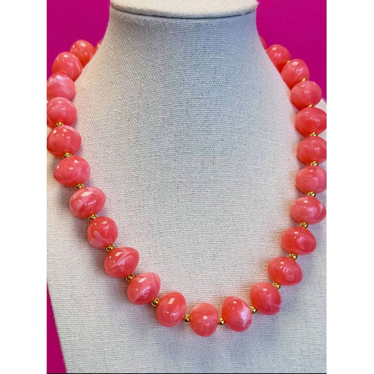 Necklace with pink beads on a mannequin against a pink background