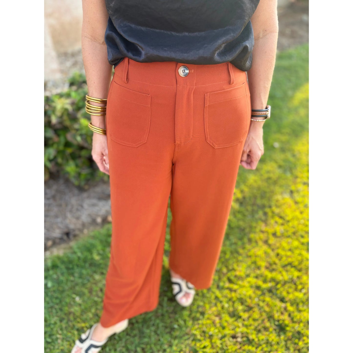 Person wearing rust-colored pants with a blurred natural background