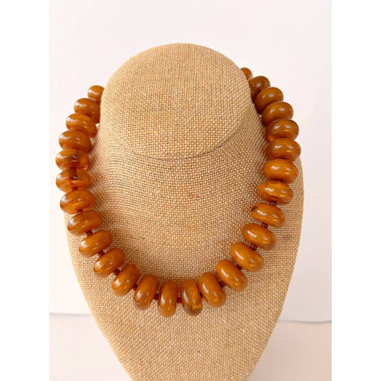 Annie Ks Boutique Rory necklace featuring large amber brown rondelle beads on a beige linen display bust