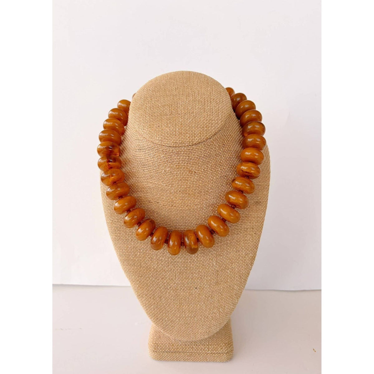 Annie Ks Boutique Rory necklace featuring large amber brown rondelle beads on a beige display bust