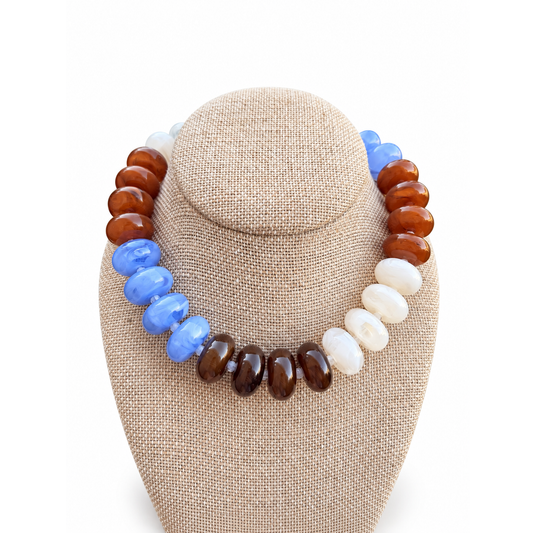 Annie Ks Boutique Autumn Sky statement necklace with color-blocked blue, amber, brown, and cream beads on a display