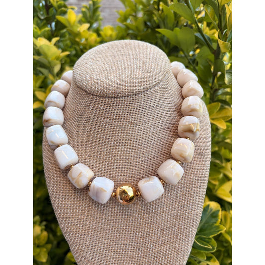 Annie Ks Boutique beige cube bead necklace featuring a polished gold ball centerpiece on a fabric display bust.