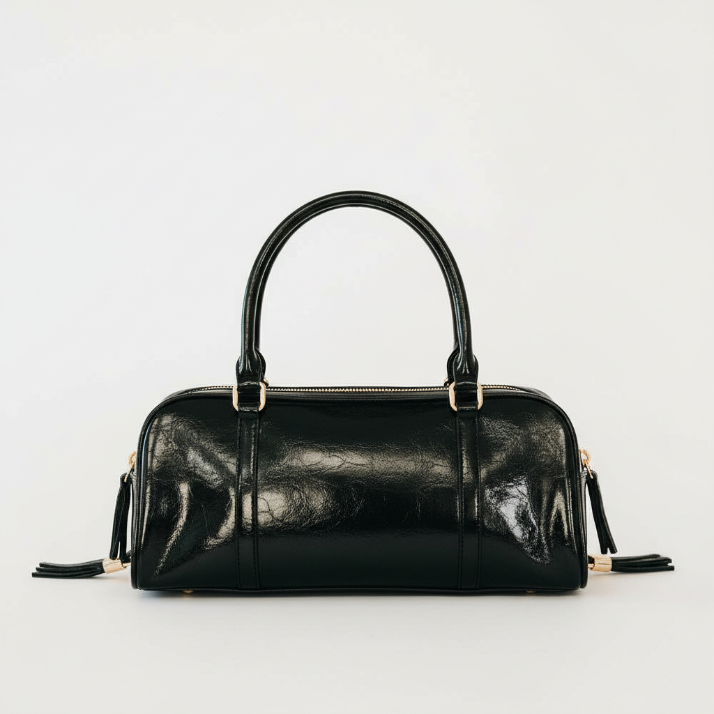 Annie Ks Boutique Arlys barrel shoulder bag in black vegan leather with top handle and gold hardware details