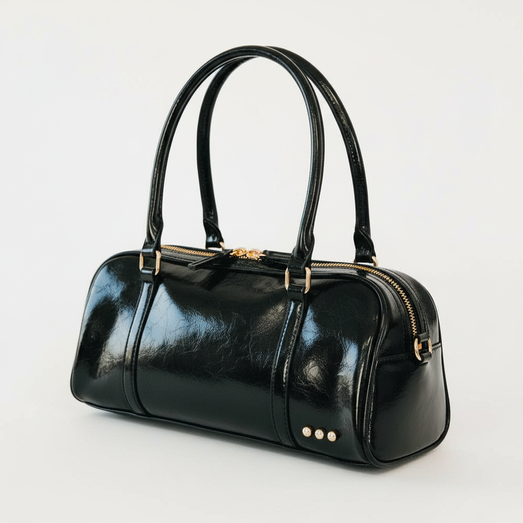 Annie Ks Boutique Arlys barrel shoulder bag in black vegan leather with top handles and gold hardware details