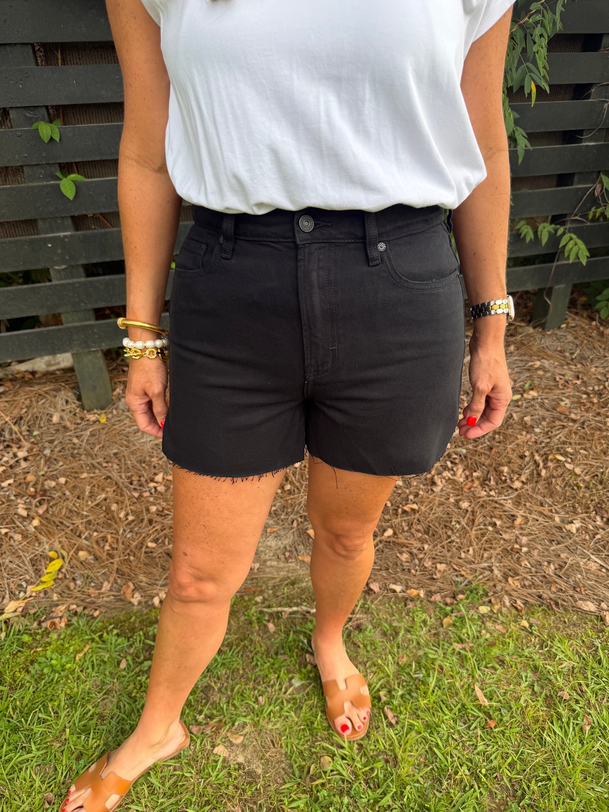 Annie Ks Boutique high-waisted black denim shorts with a raw hem and structured cotton fit worn with a white tee.