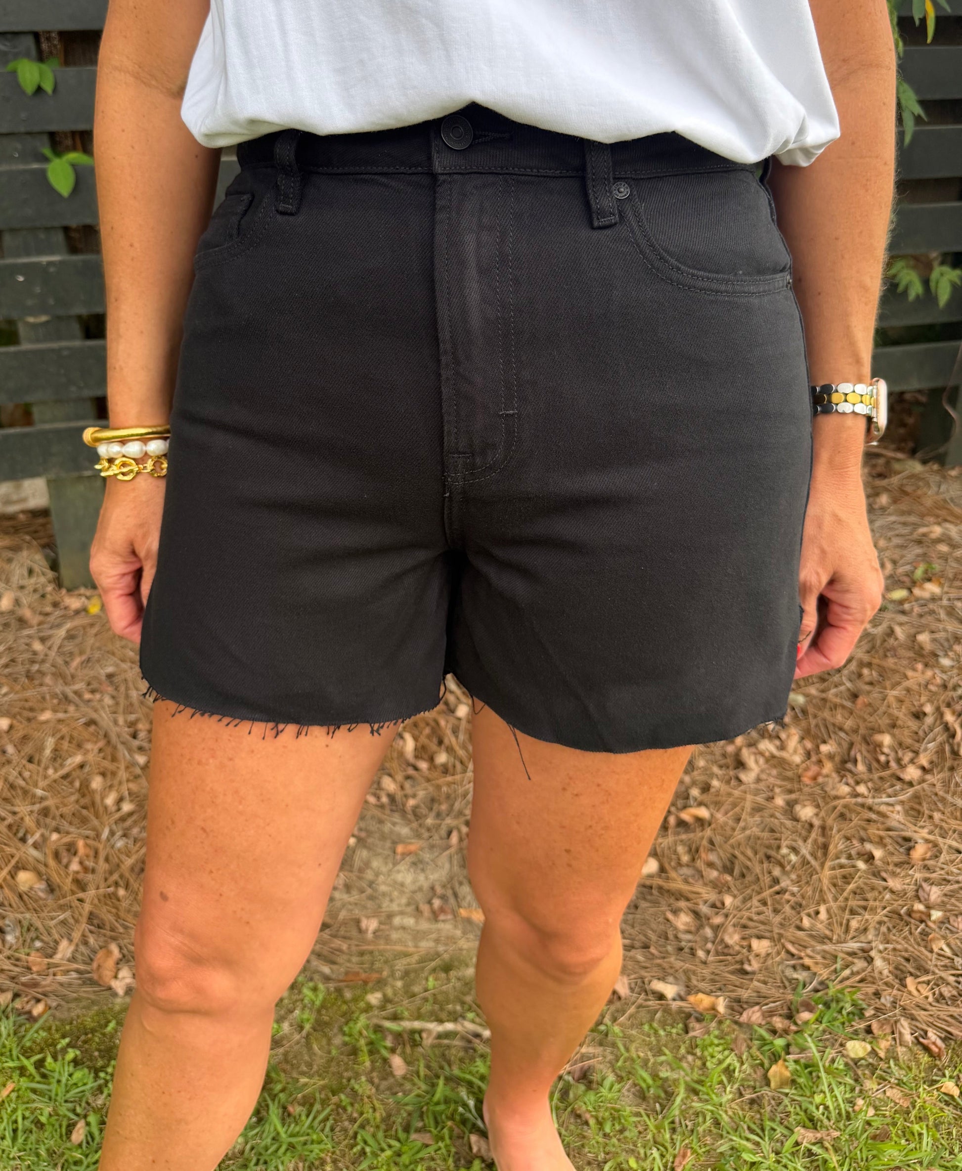 Annie Ks Boutique high-waisted black denim shorts with a raw hem, styled with a white t-shirt for a casual look.