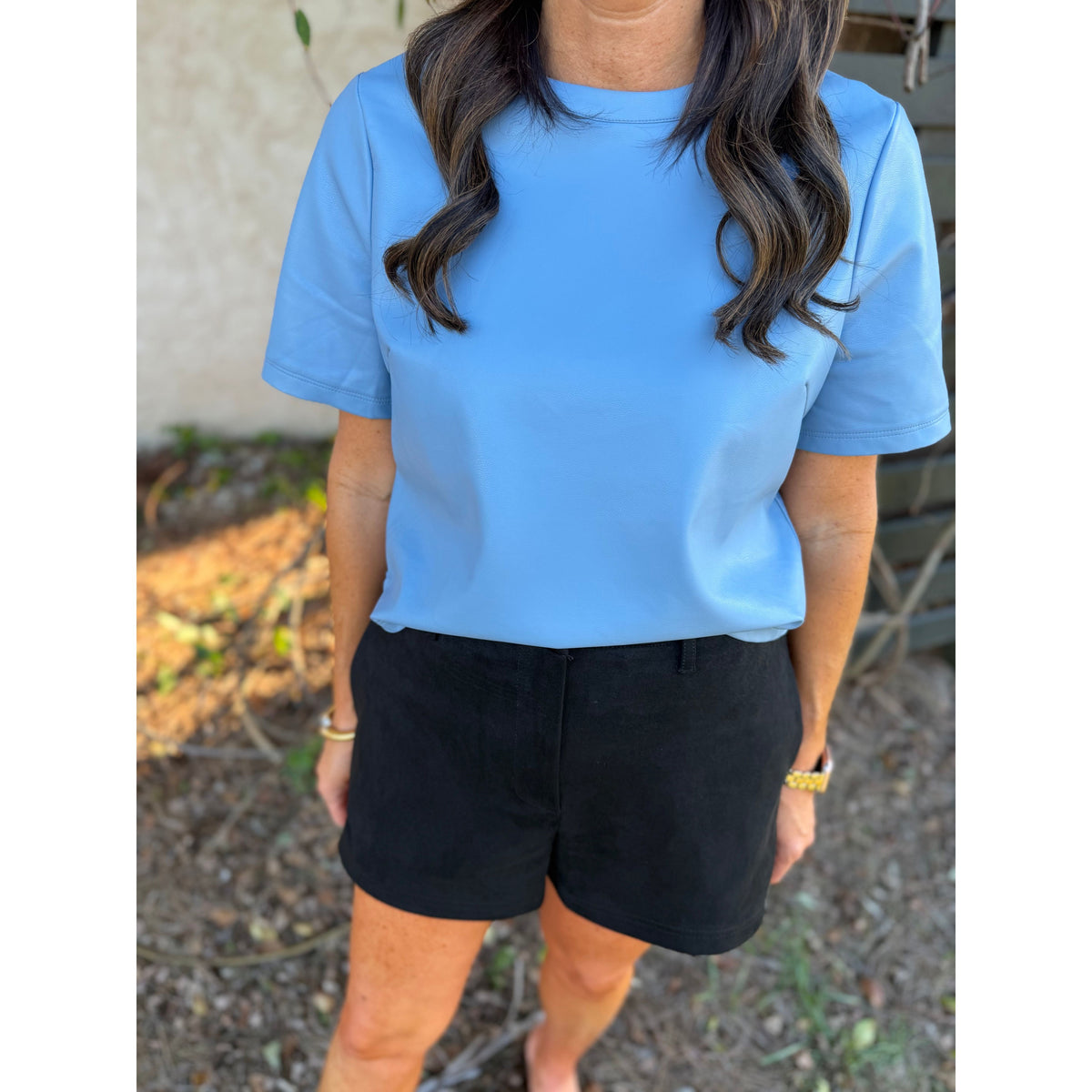 Annie Ks Boutique black faux suede shorts paired with a light blue short-sleeve top on a woman