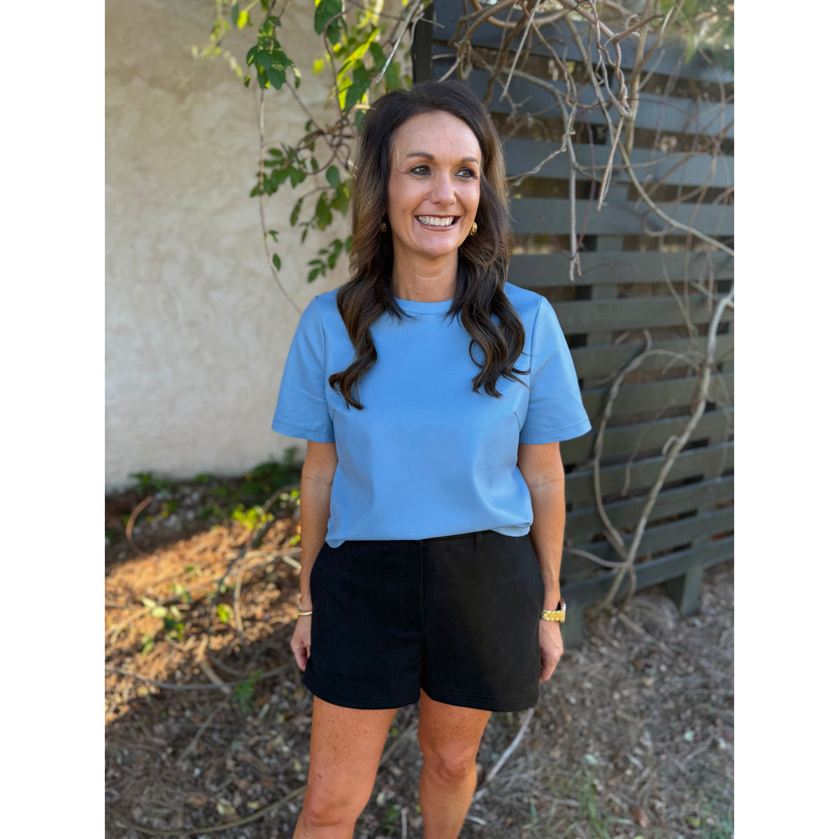 Annie Ks Boutique black faux suede shorts with a relaxed fit and side pockets worn by a smiling woman outdoors.