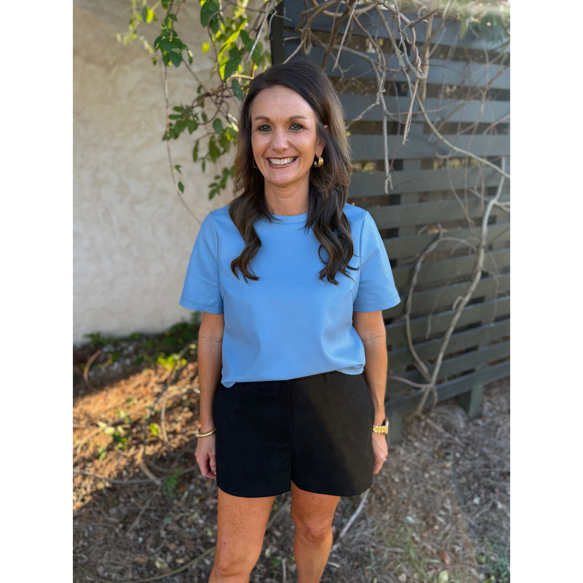 Annie Ks Boutique black faux suede shorts with a relaxed fit and side pockets worn by a smiling woman outdoors.