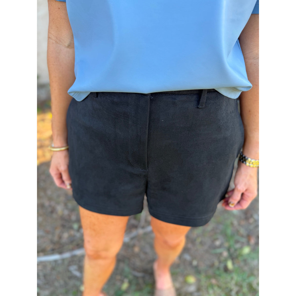 Annie Ks Boutique black faux suede shorts with a relaxed fit and belt loops, paired with a light blue top.