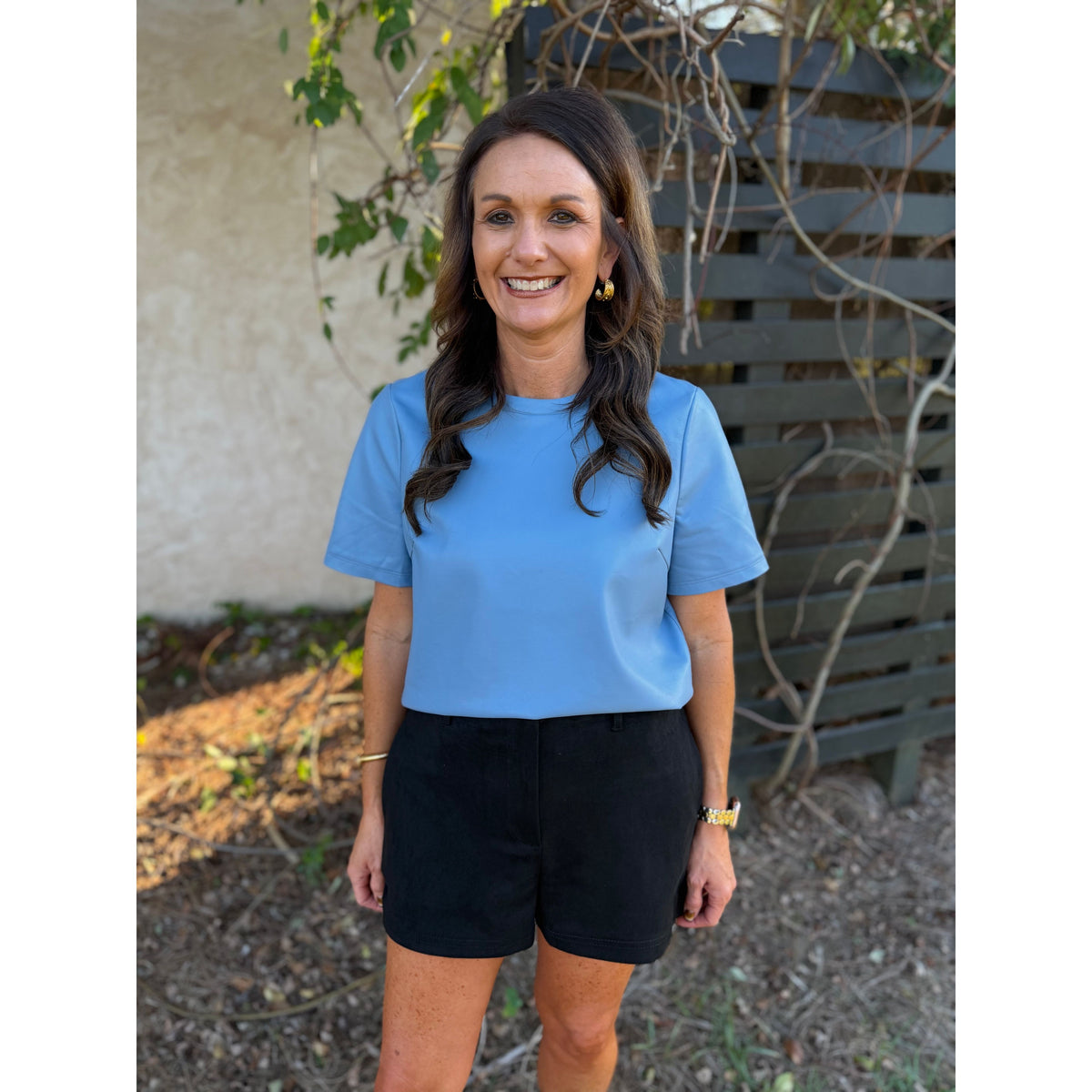 Annie Ks Boutique black faux suede shorts with a relaxed fit and side pockets worn by a woman in a blue top
