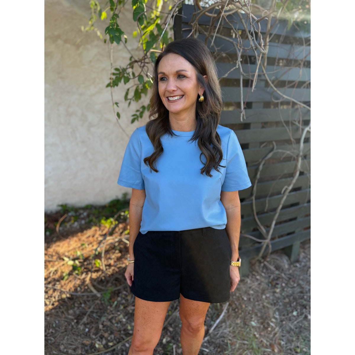 Annie Ks Boutique black faux suede shorts with a relaxed fit and side pockets, styled with a light blue top.