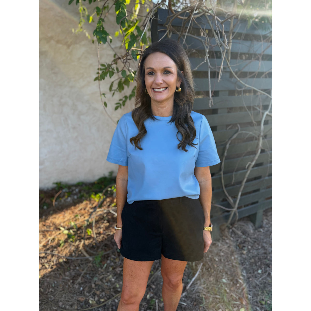Annie Ks Boutique black faux suede shorts with a relaxed fit and side pockets worn by a smiling woman outdoors