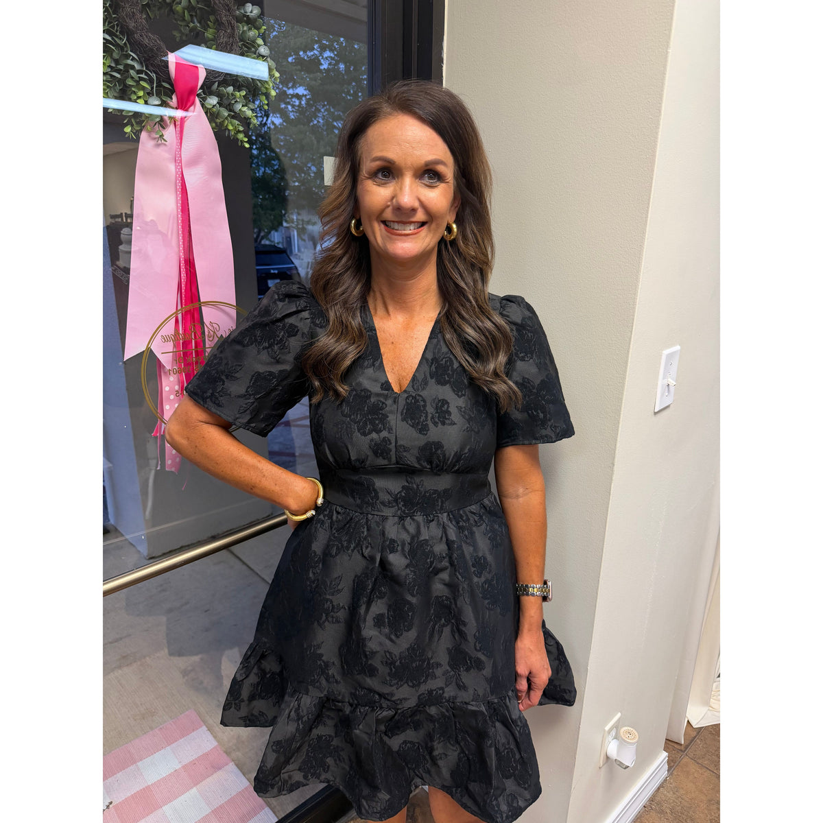 Annie Ks Boutique black jacquard mini dress with V-neck, puff sleeves, and textured floral pattern on a smiling woman
