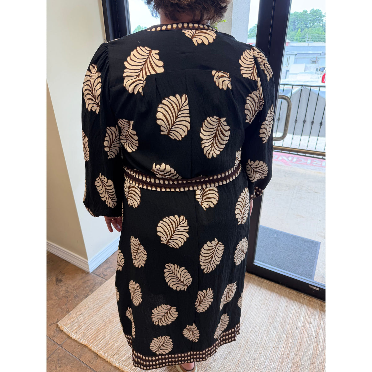 Annie Ks Boutique black midi dress with beige leaf print, featuring a belted waist and long sleeves, back view.