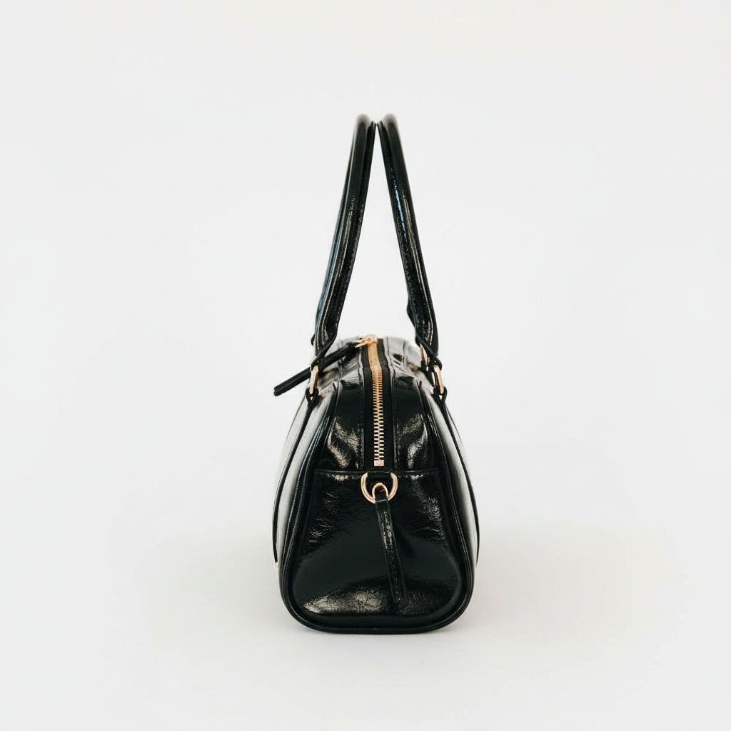 Annie Ks Boutique Arlys barrel shoulder bag in black vegan leather, side view showing zipper and handle detail.